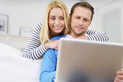 Dieses Foto veranschaulicht ein junges Paar mit Notebook bei einem Online Stromanbieterwechsel